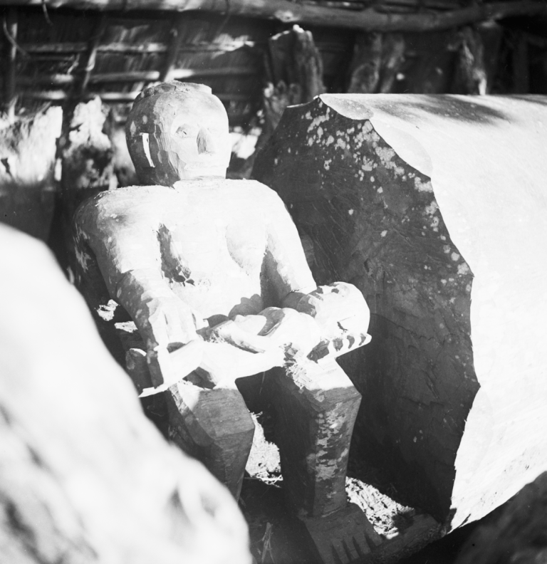 One end of an Ikoro (large slit drum) depicting a seated woman figure holding a baby in her lap. Photograph by Gwilliam Iwan Jones, 1932-1939, Ohafia, Nigeria. Image source: Jones Collection.